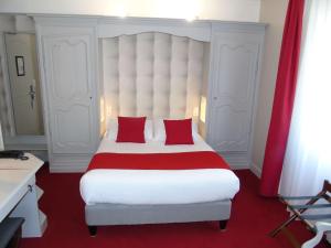 sypialnia z dużym białym łóżkiem z czerwonymi poduszkami w obiekcie Best Western Hôtel Montgomery w mieście Pontorson