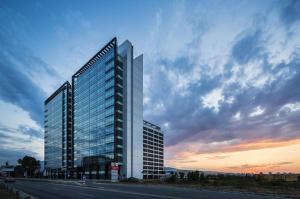 a tall building with glass windows on the side of a road at Best Western Premier Sofia Airport Hotel in Sofia