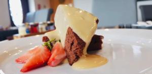 ein Stück Kuchen und Obst auf einem weißen Teller in der Unterkunft The Waterfront in Portpatrick