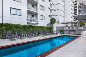a pool with chairs and a pool table in front of a building at Seamark on First in Mooloolaba