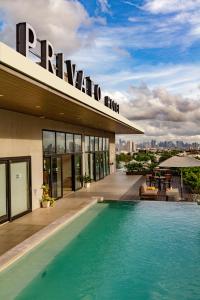 a hotel with a swimming pool in front of a building at Privato Quezon City in Manila