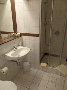 uma casa de banho branca com um lavatório e um chuveiro em Hotel Restaurant Bootshaus em Achim