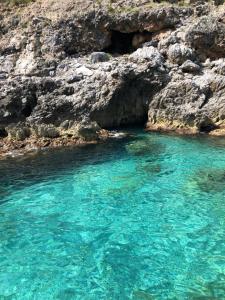 a blue pool of water next to a rocky shore at B&B Margherita in Marina di Camerota