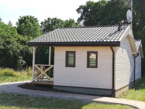 a small white shed with a wooden door at Domek nad morzem in Będzino