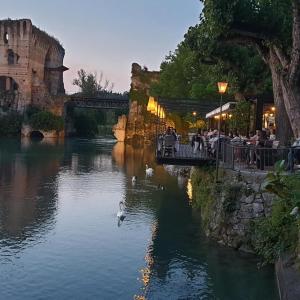 a river with people sitting at a restaurant and a duck in the water at Corte La Guarnigione in Valeggio sul Mincio