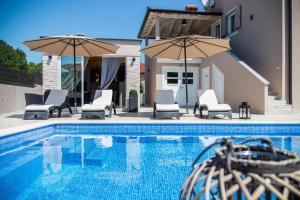 a pool with chairs and umbrellas next to a house at Villa Franka in Labin