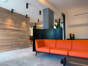 an orange couch in a lobby with a wooden wall at The Green Park Hotel in Cavallino-Treporti