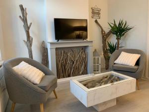 a living room with two chairs and a tv at La Maison Du Bois Flotté in Boulogne-sur-Mer