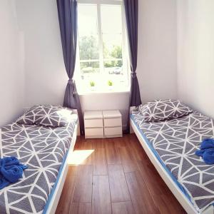 two beds in a room with a window at Apartament w starej kamienicy in Mrągowo