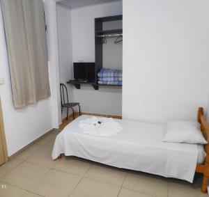 a bedroom with a white bed and a chair at Imperial Hotel in Foz do Iguaçu