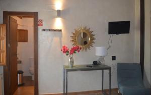 a room with a table with a vase of flowers and a mirror at Santa Brigida - Real 1 in Hontanas