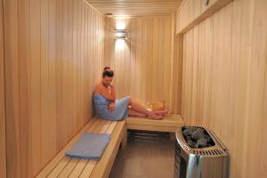 a woman sitting on a bench in a sauna at Nestor Hotel in Ayia Napa