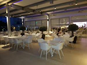 a restaurant with white tables and white chairs at Nestor Hotel in Ayia Napa