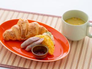 a plate with sausage and bread and a cup of soup at Hotel Waraku Shibukawa in Shibukawa