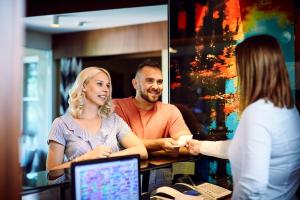 a group of people standing around a counter with a woman at Hotel Lajta Park in Mosonmagyar&oacute;v&aacute;r
