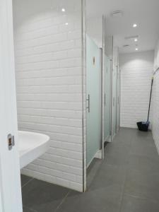 uma casa de banho com paredes brancas e um lavatório e bancas em Albergue Casa Sueño em Salas