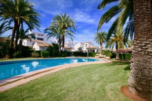 una piscina con palmeras y casas en Puerto Azul 5 en Dénia