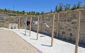 a row of shirts hanging on wooden poles next to a stone wall at Santa Brigida - Real 1 in Hontanas