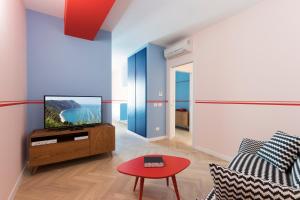 ein Wohnzimmer mit einem TV und einem roten Tisch in der Unterkunft Metropolitan Suites in Ancona