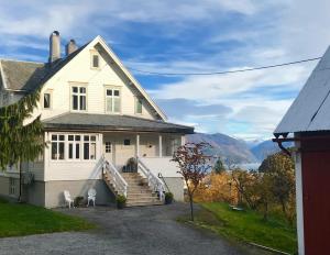 a white house with stairs and views of the mountains at Fjord View Apartment in Stranda