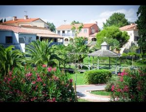 a garden with a gazebo and trees and houses at T3 duplex malibu village pass piscine en supplément 2 a 8 personnes in Canet-en-Roussillon