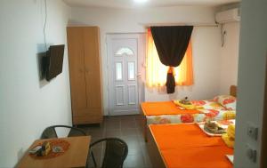 Cette chambre comprend 2 lits, une table et une porte. dans l'établissement Studio Isakovic Centar, à Sokobanja