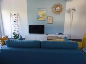 a blue couch in a living room with a tv at Côte et Mer in Le Portel