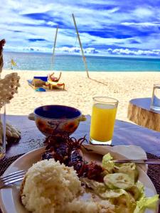 a plate of food and a glass of beer on the beach at White Beach Front and Cottages in Buruanga