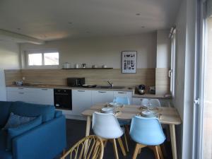 a kitchen with a table and chairs and a blue couch at Côte et Mer in Le Portel