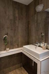 La salle de bains est pourvue d'un lavabo blanc et de murs en bois. dans l'établissement Sun Frediano Suites Florence, à Florence