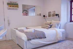 Cama blanca en habitación blanca con espejo en Casa com Graça - Fully equiped Studio in the Historical Center, en Lisboa