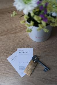 a key on a table next to a vase of flowers at Sun Frediano Suites Florence in Florence