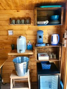 a kitchen with wooden walls and shelves with appliances at Locations insolites "vie en plein air" cabane Bastide Bellugue maison d'hôtes reseau Bienvenue à la ferme à 3 mn de lourmarin in Cadenet
