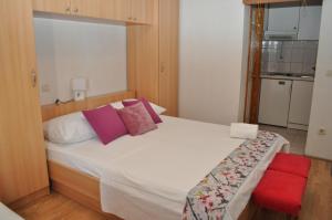 - une chambre avec un grand lit blanc et une chaise rouge dans l'établissement Apartments Veselko, à Makarska