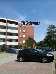 Czarny samochód zaparkowany przed budynkiem w obiekcie FeWo Schwarz w mieście Dornumersiel