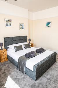 two beds in a bedroom with two tables and lamps at Babbacombe Apartments in Torquay