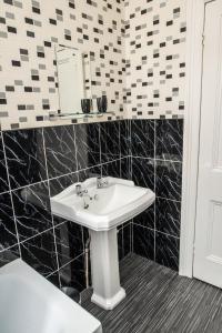 a bathroom with a sink and black and white tiles at Babbacombe Apartments in Torquay