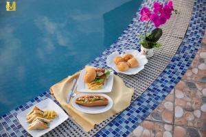 a table with plates of food next to a swimming pool at Merry Land Hotel Da Nang in Danang