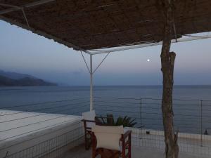 a porch with a table and chairs and the ocean at Christos Rooms in Palaiochóra +50 photos