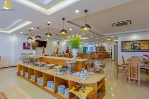 a restaurant with a table with dishes on it at Merry Land Hotel Da Nang in Danang