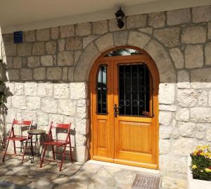 a stone building with a wooden door and chairs at Apartment Iris in Drasnice