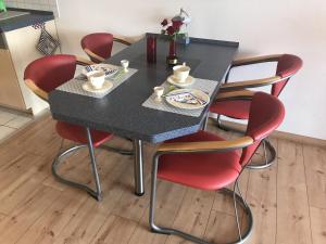 einen schwarzen Tisch mit roten Stühlen in der Küche in der Unterkunft Ferienwohnung direkt am Ryck- Nähe UNI und Kliniken in Greifswald
