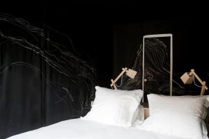 a bed with two white pillows and a black wall at Hotel The Exchange in Amsterdam