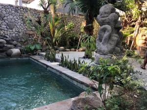 a swimming pool in a garden with a stone wall at Melati Bali 2 in Canggu