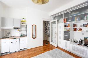a kitchen with white cabinets and a hardwood floor at Bright Lights, Big City Studio in Budapest