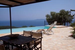 a patio with a table and chairs next to a pool at Villa Boubouki in Évyiros