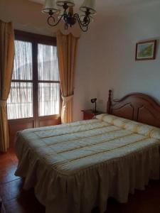 a bedroom with a large bed and two windows at Apartamento Ruta de las Nieves in Capileira