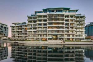 a large apartment building with its reflection in the water at 706 Canal Quays in Cape Town