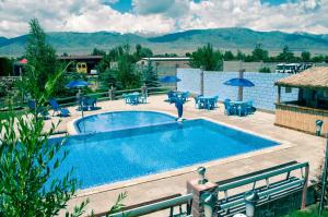a pool with chairs and umbrellas on a patio at Zlata Inn in Tamchy