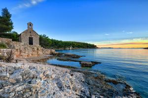 an old church on the shore of a body of water at Apartmani Rita in Milna